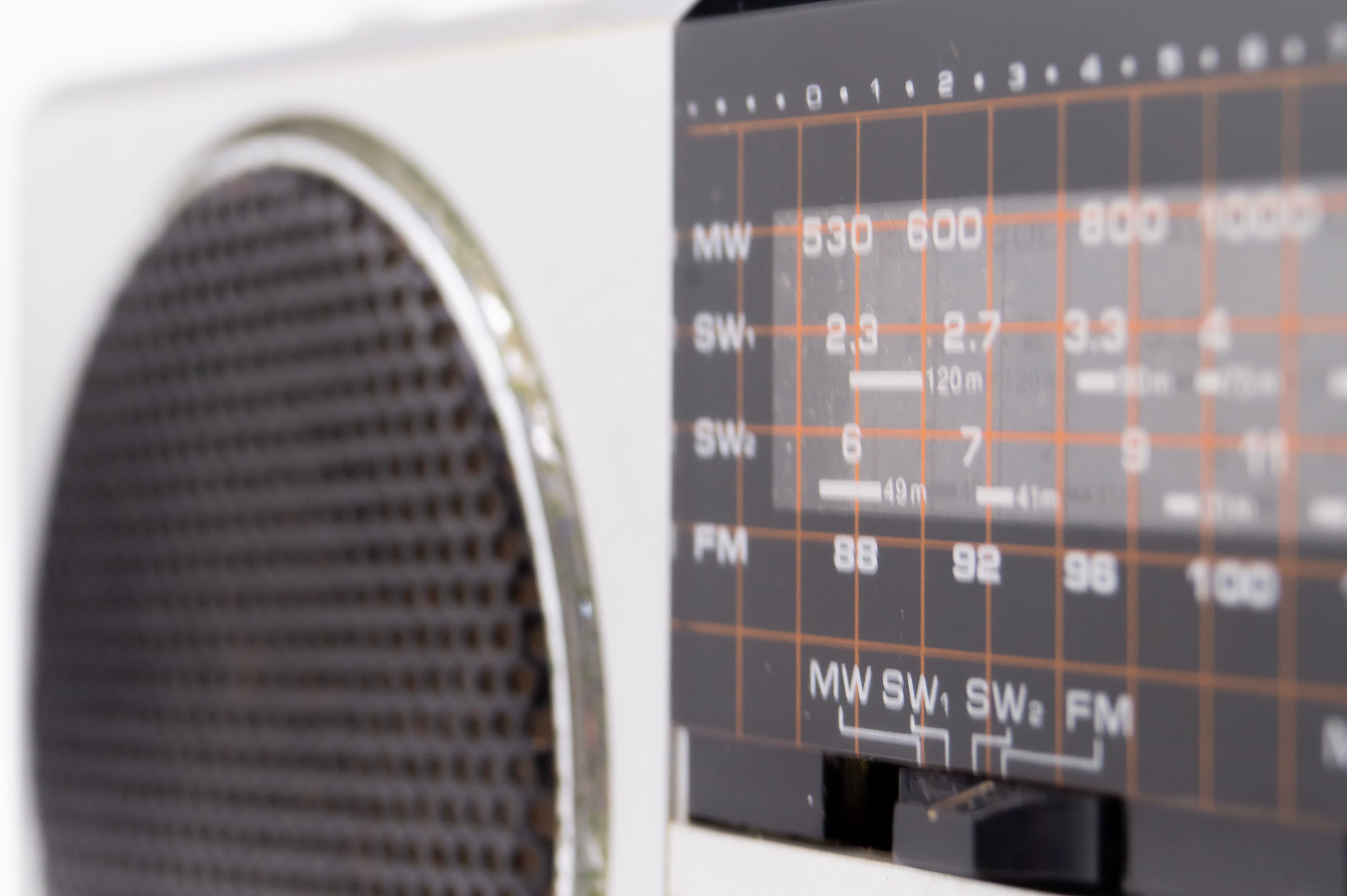 A vintage radio's tuning dial, with the MW and FM bands, beside its speaker grille